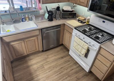 A kitchen with wood cabinets, a dishwasher, a sink, a stove with two towels, a toaster oven, a coffee maker, and various items on the countertop.